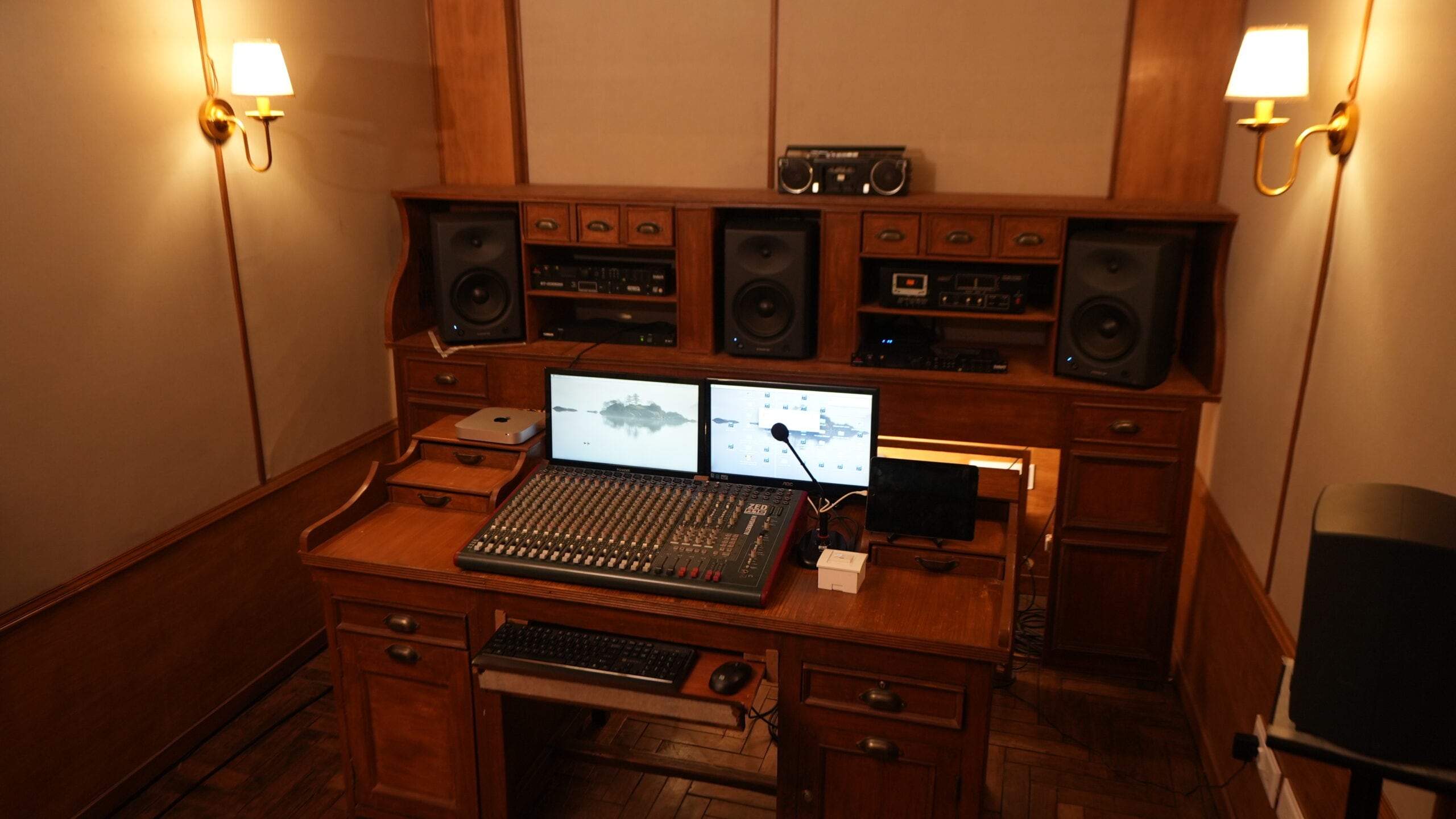 A vintage wooden console desk with an Allen & Heath mixer and three near-field monitors