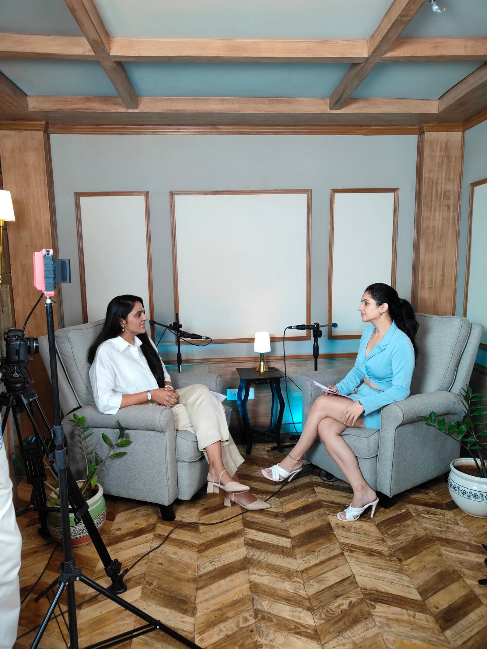 Two women in conversation on an interview set with armchairs and a herringbone floor